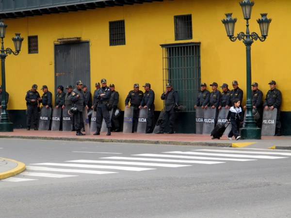Police in riot gear while school boy walks slowly by, unconcerned