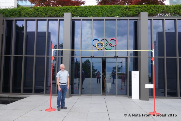 At the main entrance, Tim standing under the high jump pole set at the current record. Tim is 6"1"